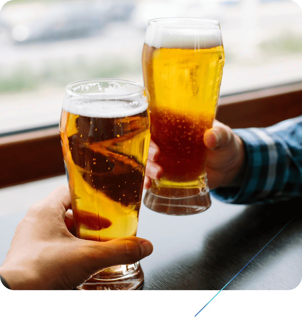 Close-up of two people clinking tall glasses of beer.