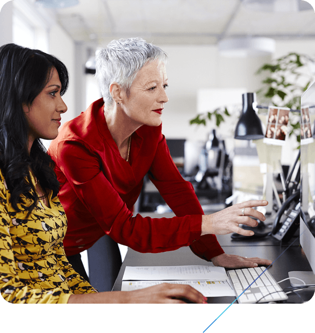 Two women in an office looking at a computer together